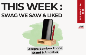Text above reads "This Week: Swag We Saw and Liked." Below is an image of the Allegra Bamboo Phone Stand and Amplifier holding a phone and a pen.