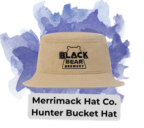 blog headers 12 - Sonic Promos | Custom Promotional Items Beige bucket hat with a Black Bear Brewery logo on a blue‑purple painted backdrop; label reads'Merrimack Hat Co. Hunter Bucket Hat'.