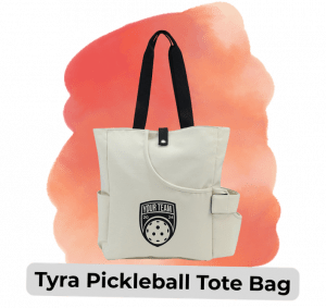 swag we saw and liked 813 11 - Sonic Promos | Custom Promotional Items Cream tote bag with black handles, front badge labeled'YOUR TEAM' with a pickleball graphic, designed for carrying pickleball gear; overlay text reads 'Tyra Pickleball Tote Bag'.