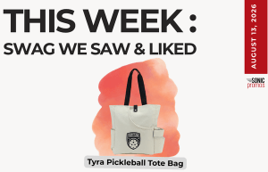 Promo graphic featuring a beige Tyra Pickleball Tote Bag with black handles on a pink splash, captioned 'This Week: Swag We Saw & Liked' with a vertical date rail showing August 13, 2026.