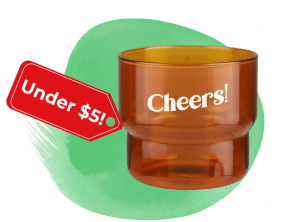 Amber glass tumbler with the word 'Cheers!' and a red 'Under !' tag on a green splash background.