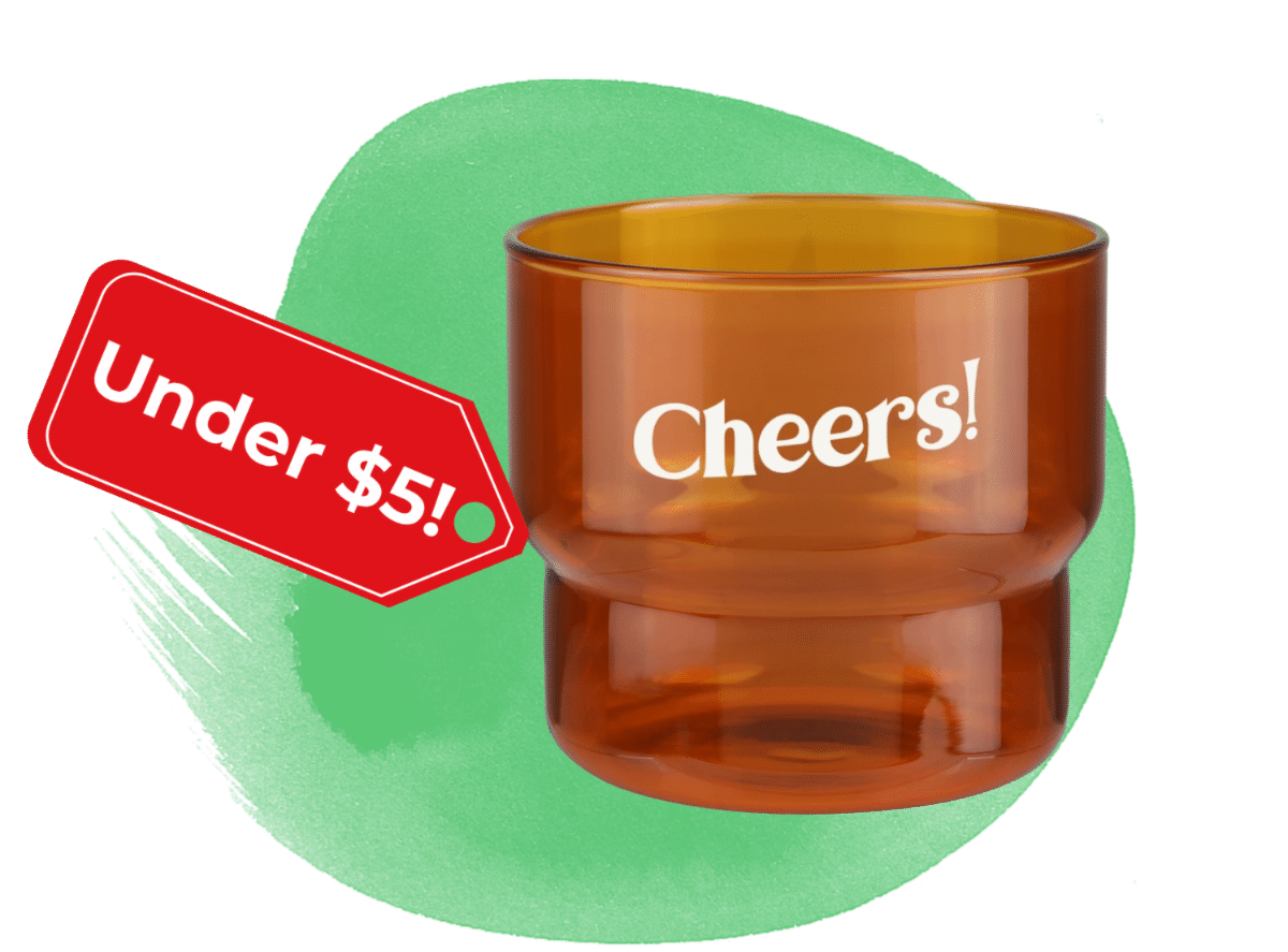 Amber glass tumbler with the word 'Cheers!' and a red 'Under $5!' tag on a green splash background.